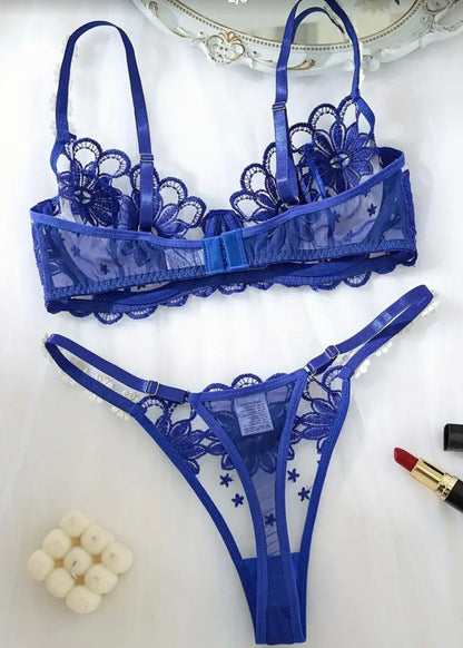 Blue lace lingerie set on a white surface with a decorative plate in the background.