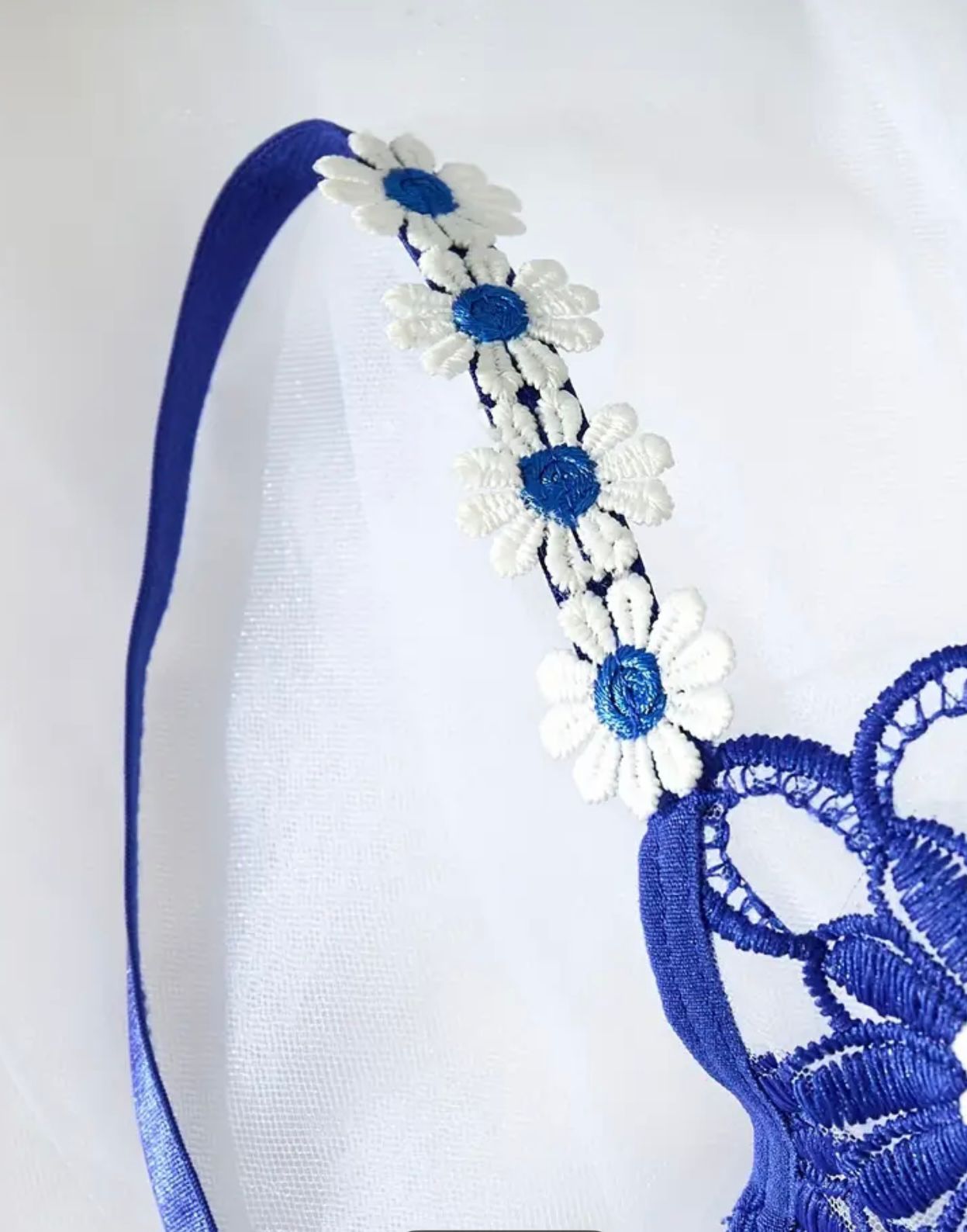 Blue headband with white floral decorations on a white background