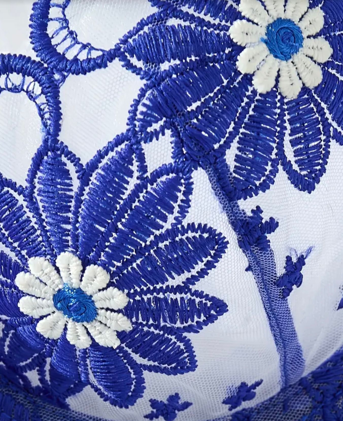 Close-up of blue and white floral embroidery on a white background