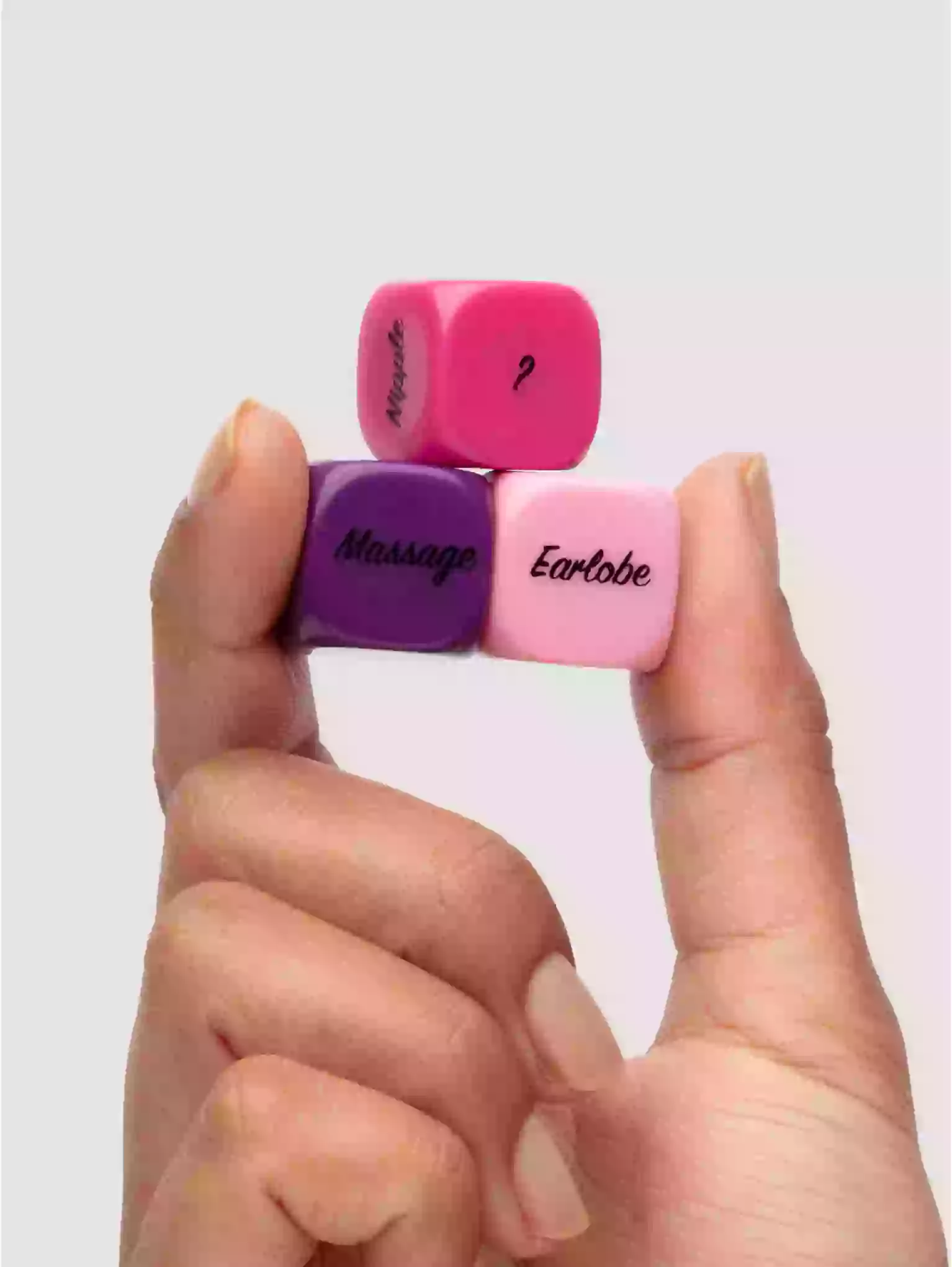 Three small dice with text on a hand against a light gray background