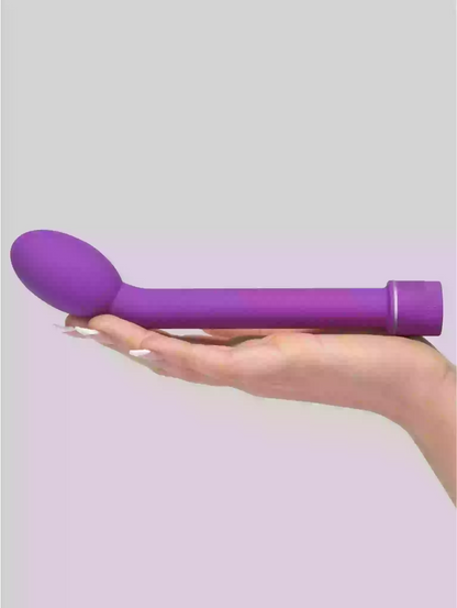 Purple handheld massager held in a hand against a light gray background