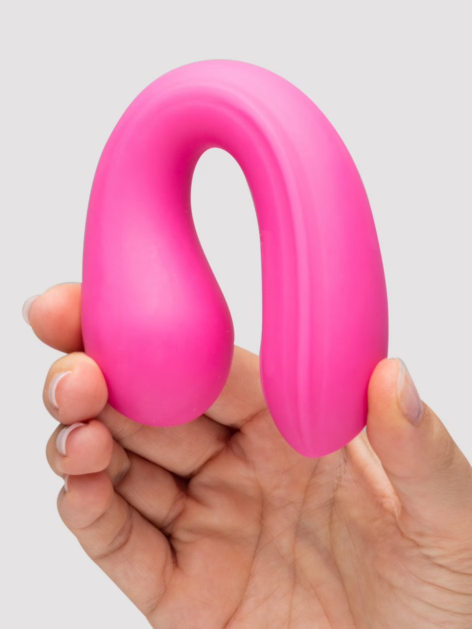 Pink silicone ring held in a hand against a light gray background