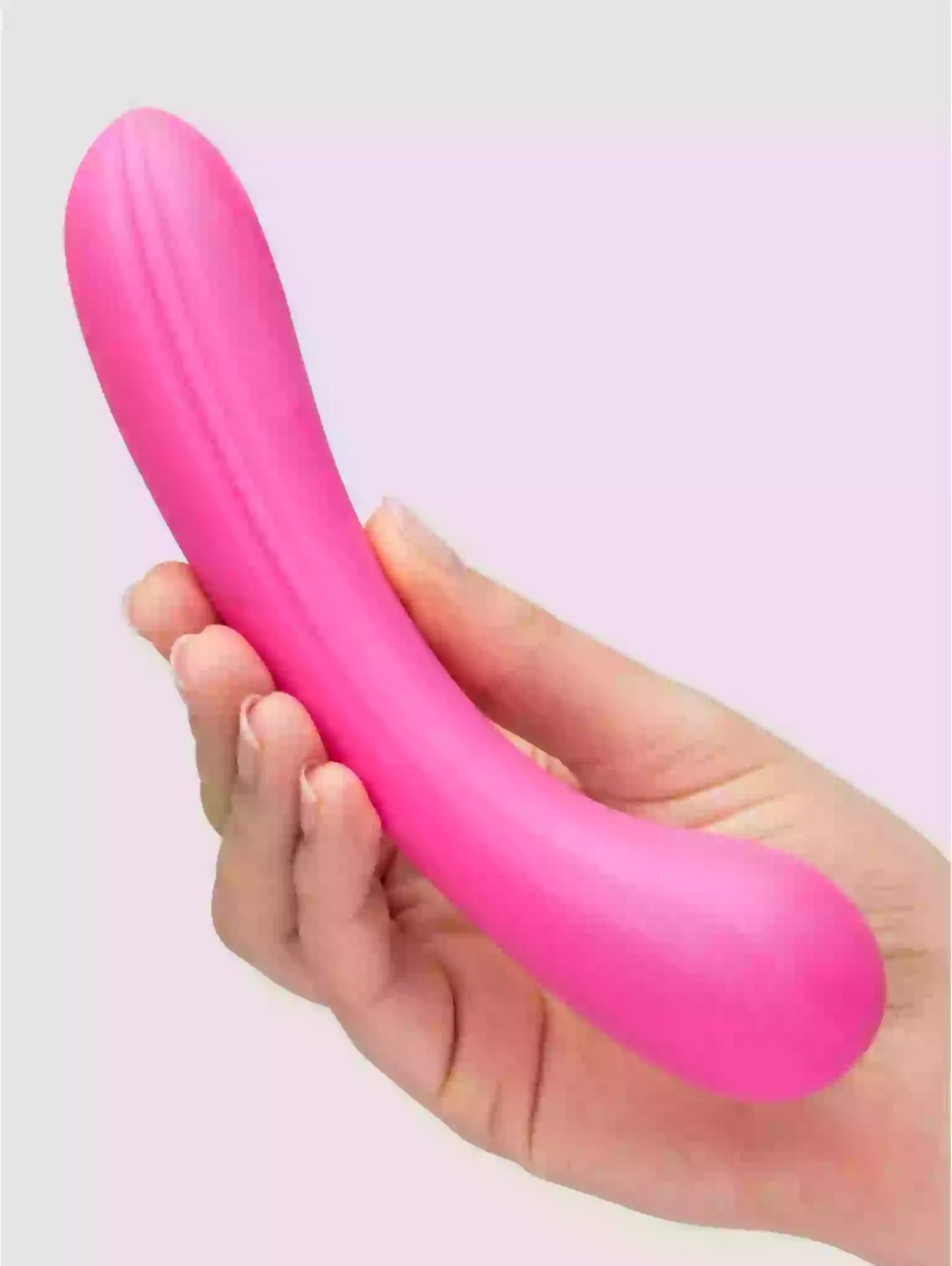 Pink balloon being held by a hand against a light pink background