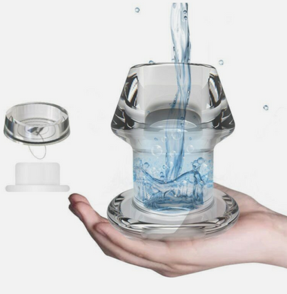 Glass container with water being poured into it held in a hand against a white background
