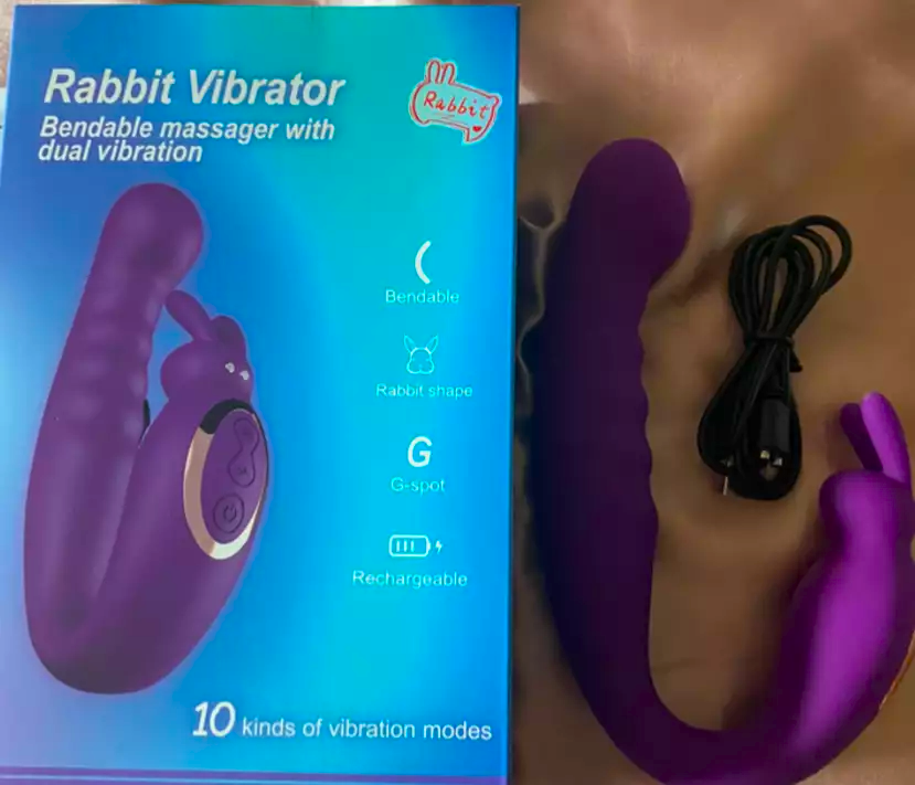 Purple rabbit vibrator with packaging and charging cable on a beige surface