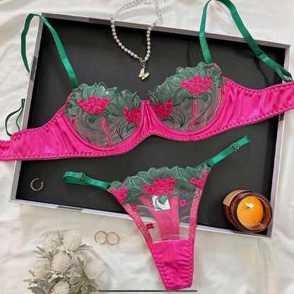 Pink and green lingerie set with jewelry on a black tray.