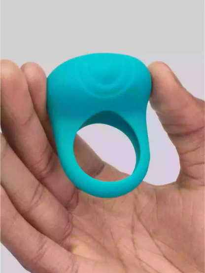 Turquoise silicone ring held in a hand against a neutral background