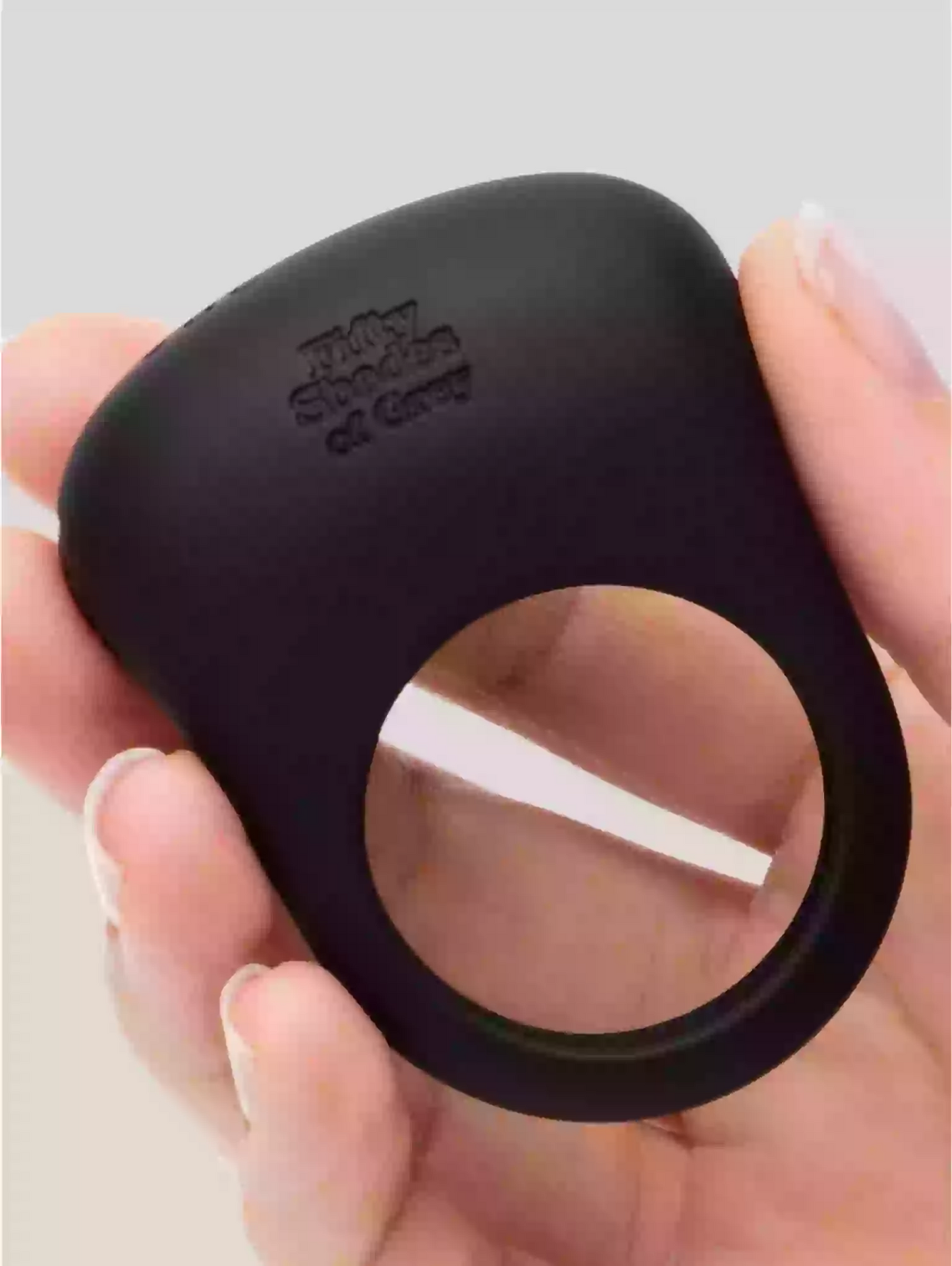 Black silicone ring held in a hand with a light gray background