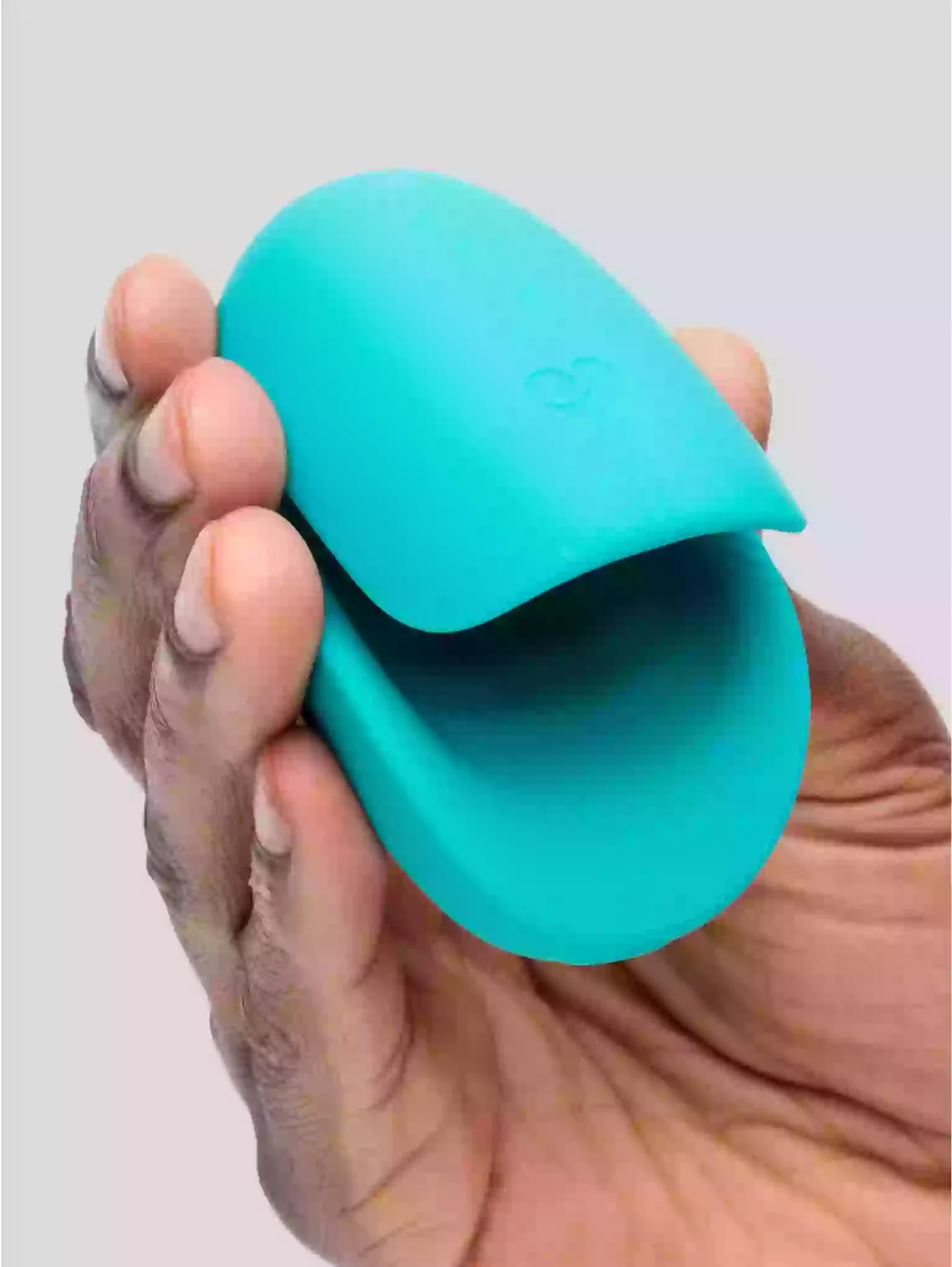 Turquoise silicone cupping tool held in a hand against a light gray background