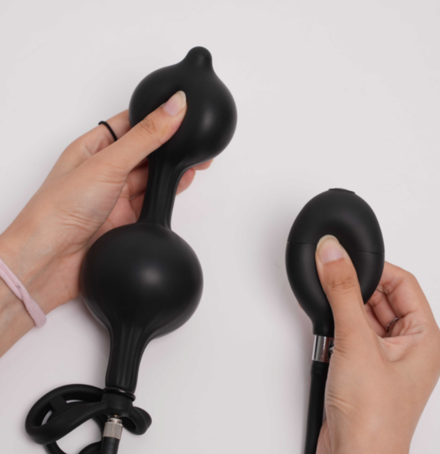Two black massage tools held by hands on a white background