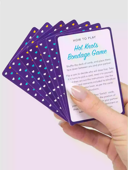 Hand holding a card from a 'Hot Knots Bondage Game' with purple and white design.