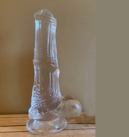 Clear glass boot-shaped object on a wooden surface with a beige wall background