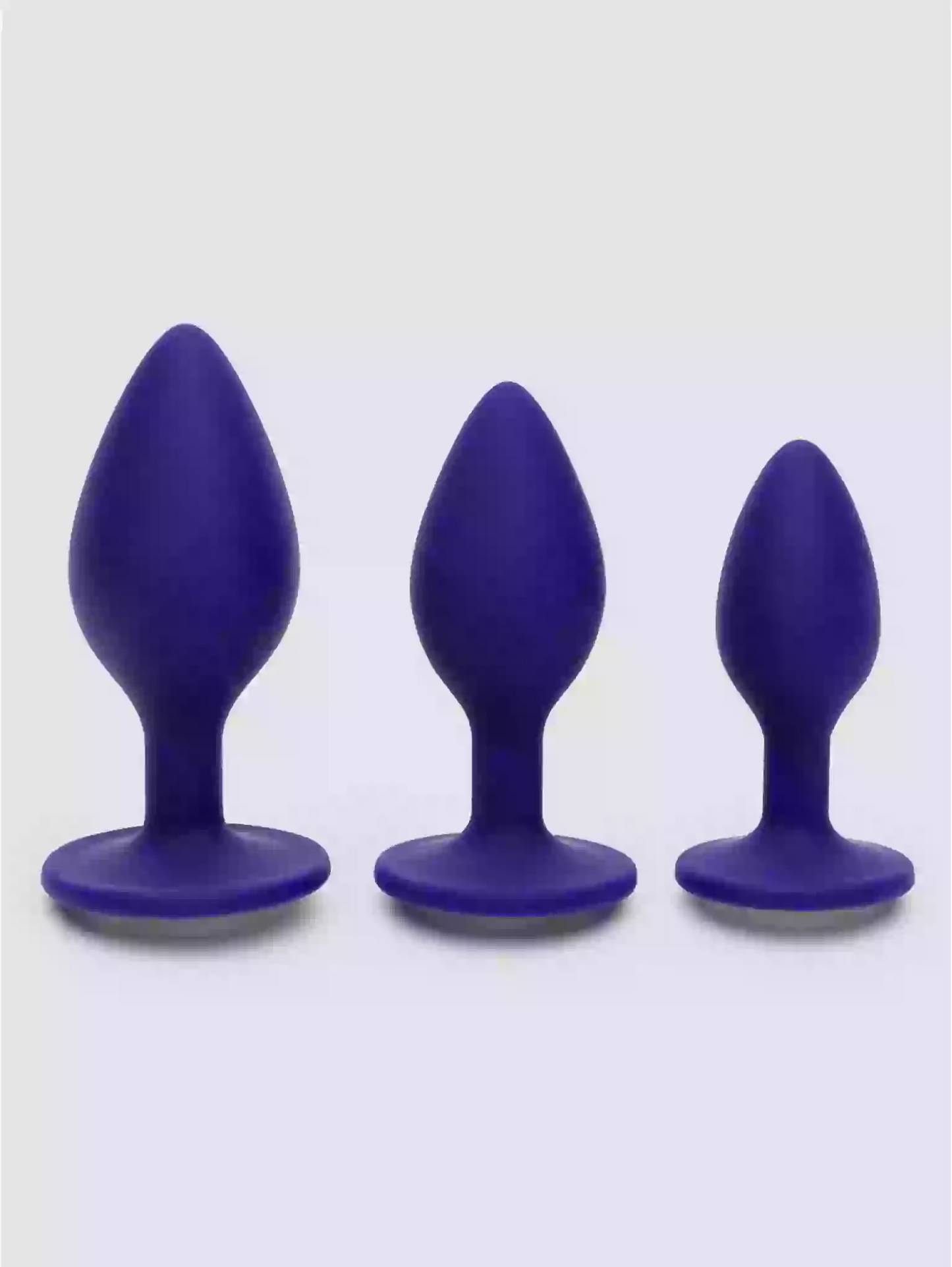 Three purple silicone butt plugs of different sizes on a white background