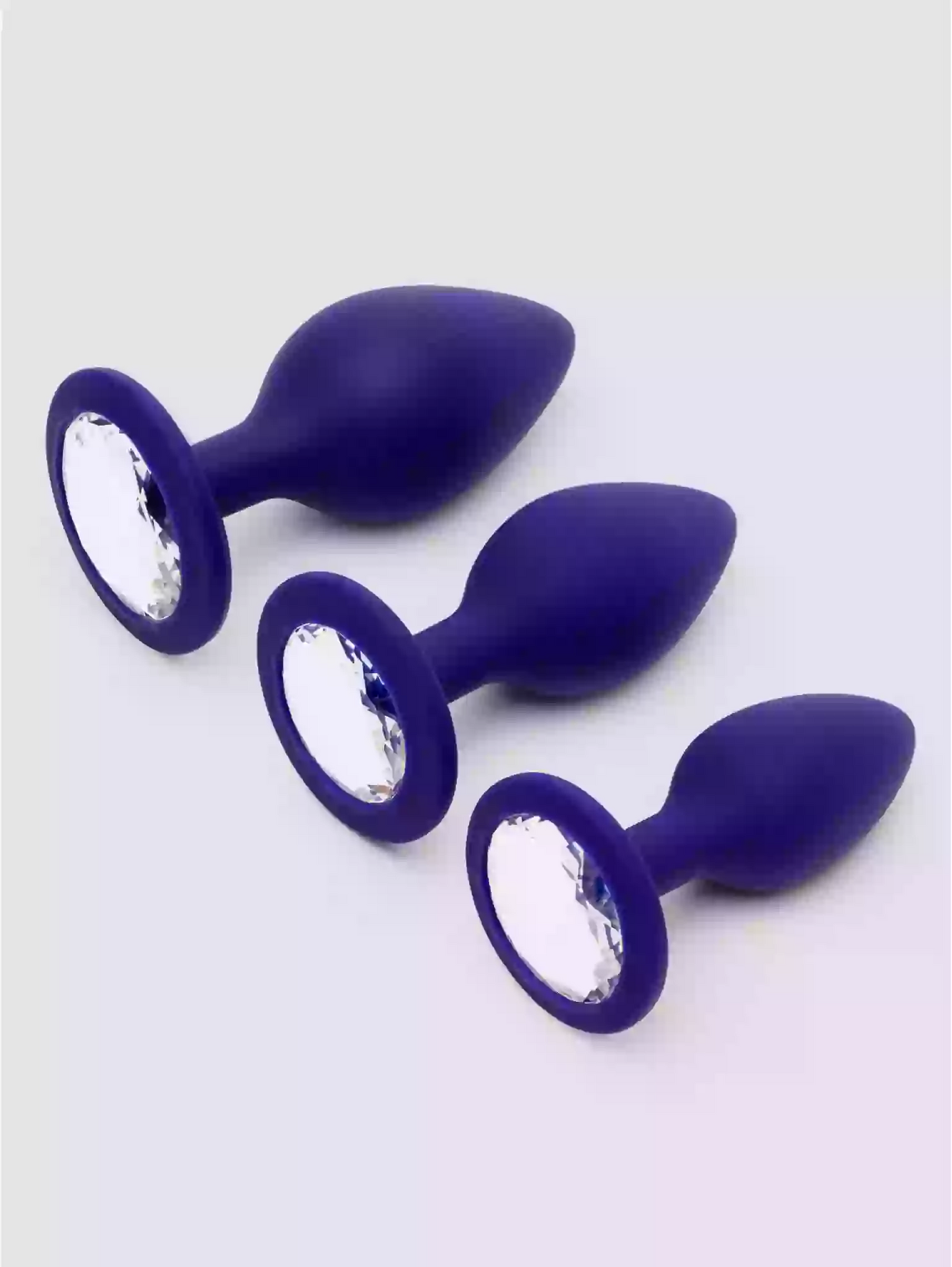 Three purple silicone butt plugs with crystal embellishments on a white background