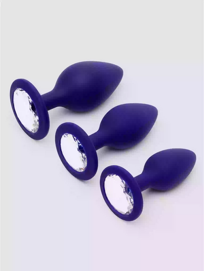 Three purple silicone butt plugs with crystal embellishments on a white background