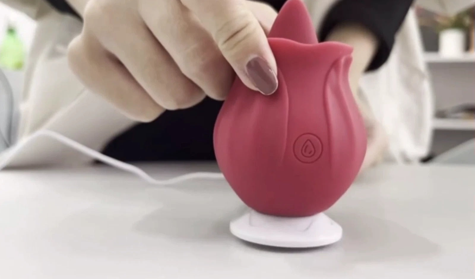 Red silicone bulb with suction cup held by a hand on a light surface.