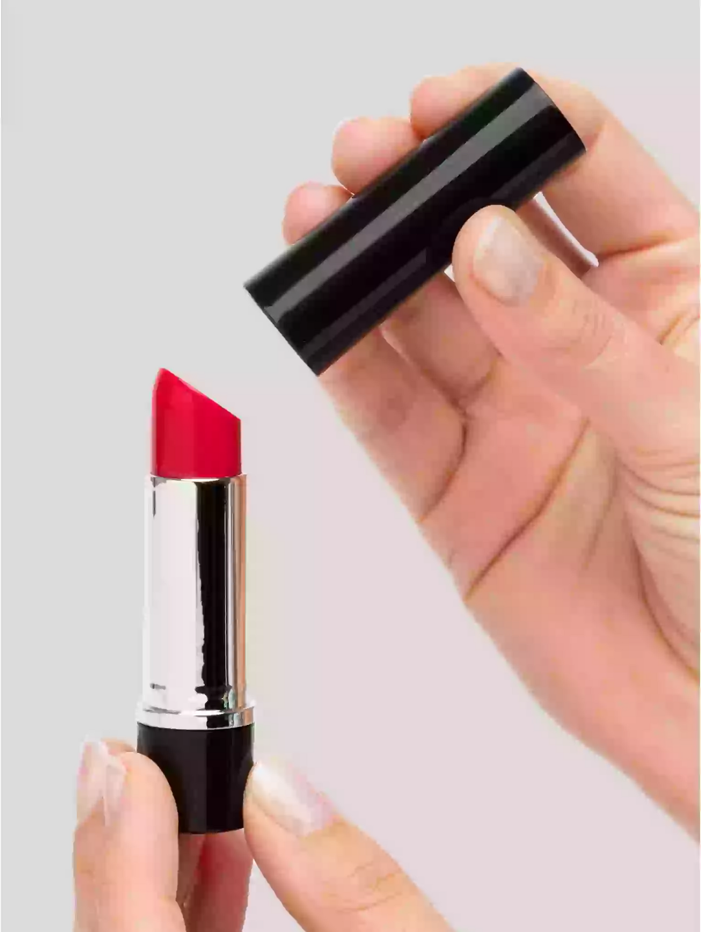 Red lipstick with black casing held by a hand against a light gray background