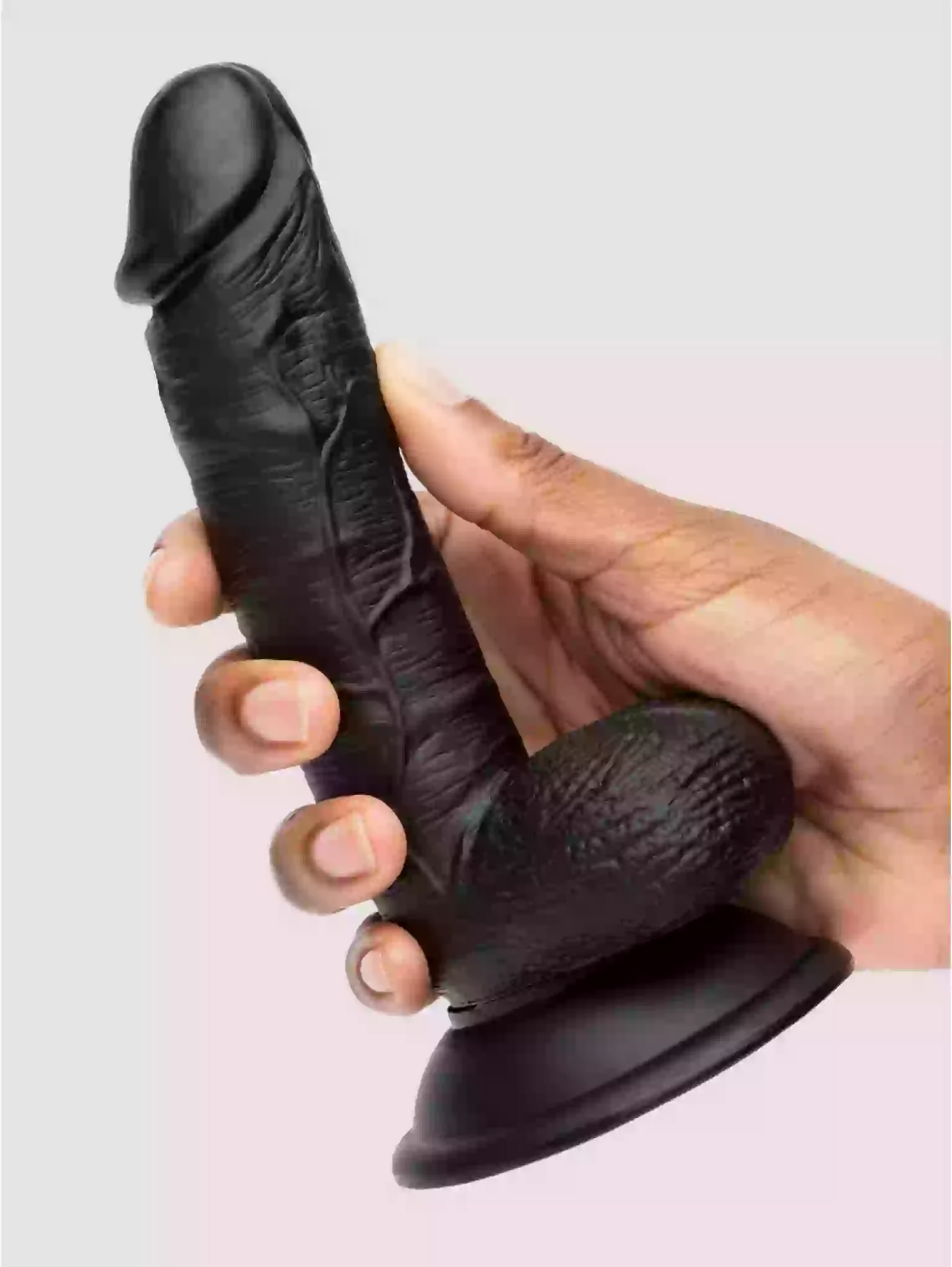 Black silicone suction cup with textured design held by a hand against a light gray background
