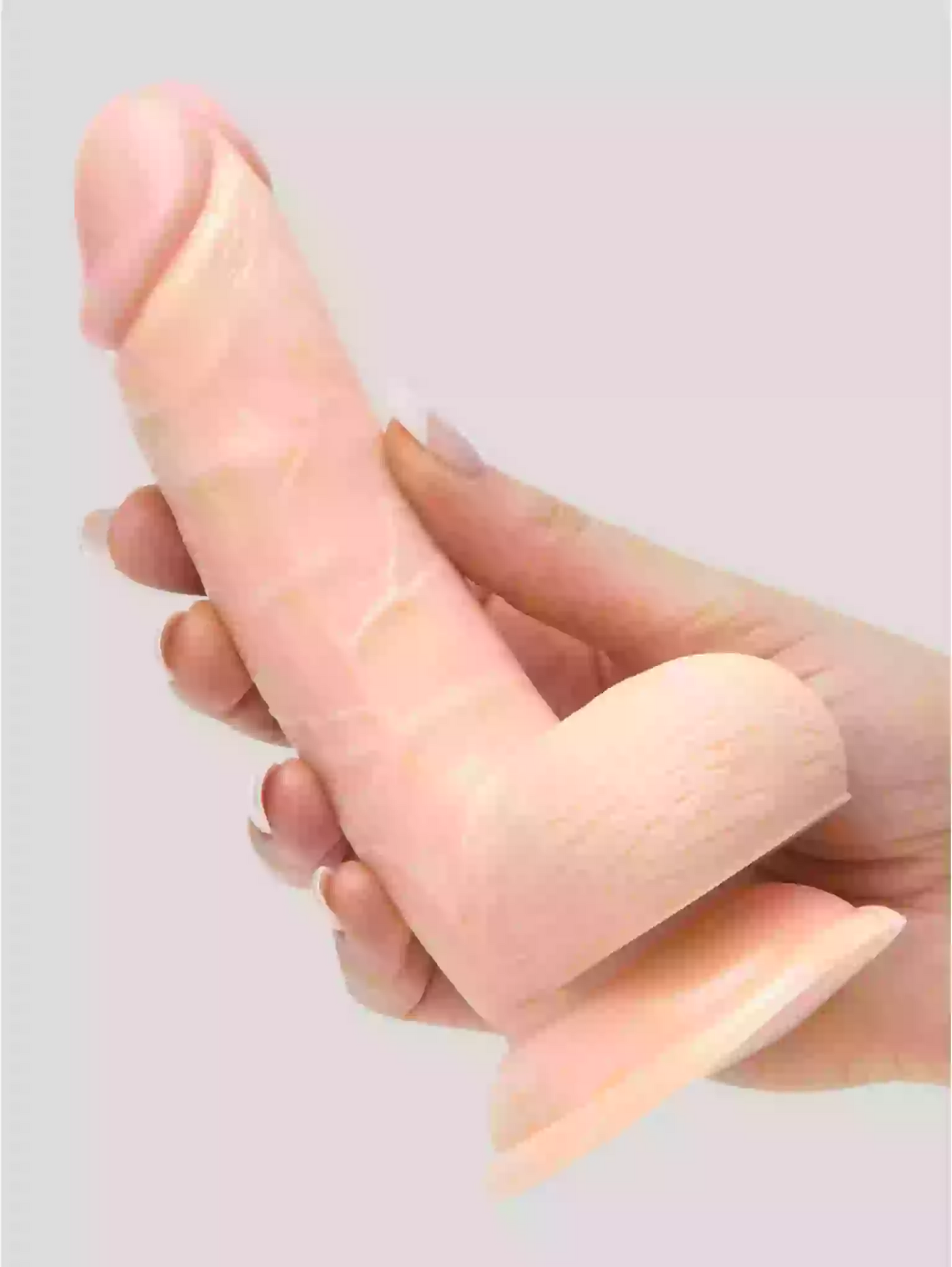 Close-up of a hand holding a silicone ring against a light pink background