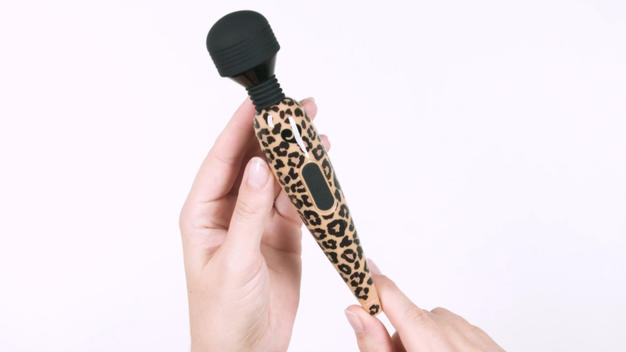 Hand holding a leopard print electronic device against a white background