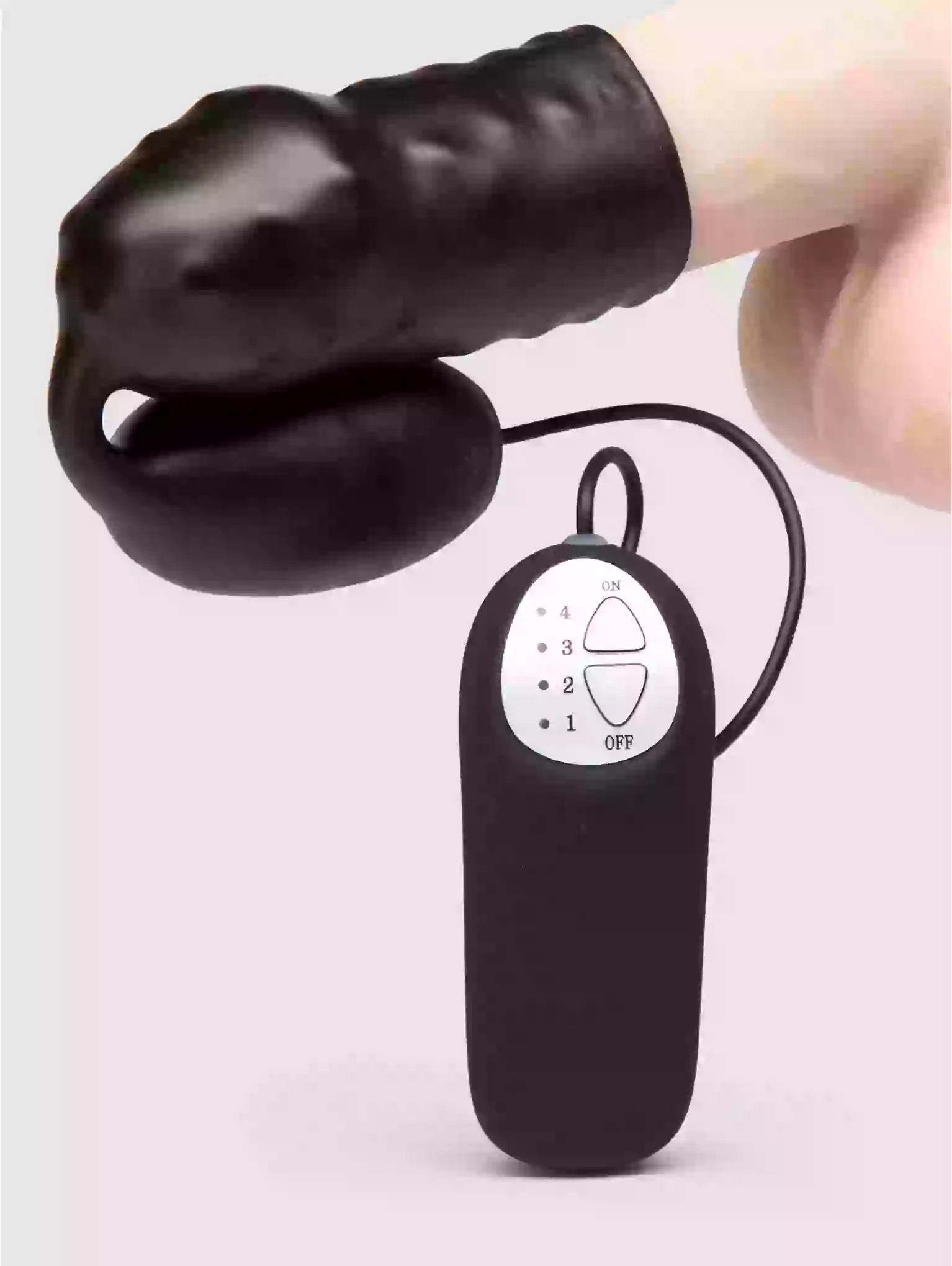Black electronic device with a hand holding it on a light pink background