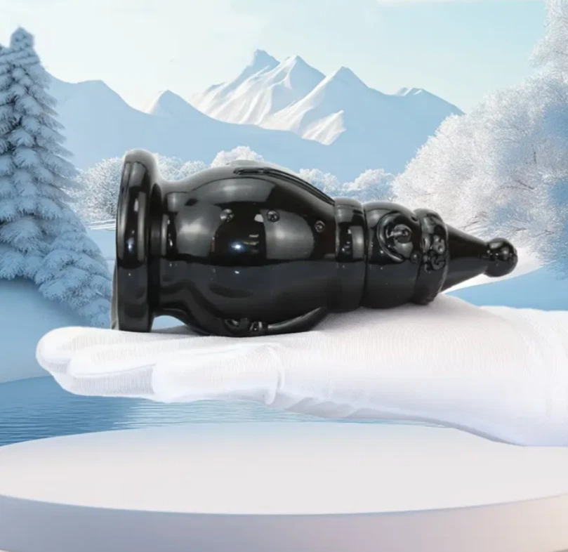 Black wine bottle held by a hand against a snowy mountain landscape