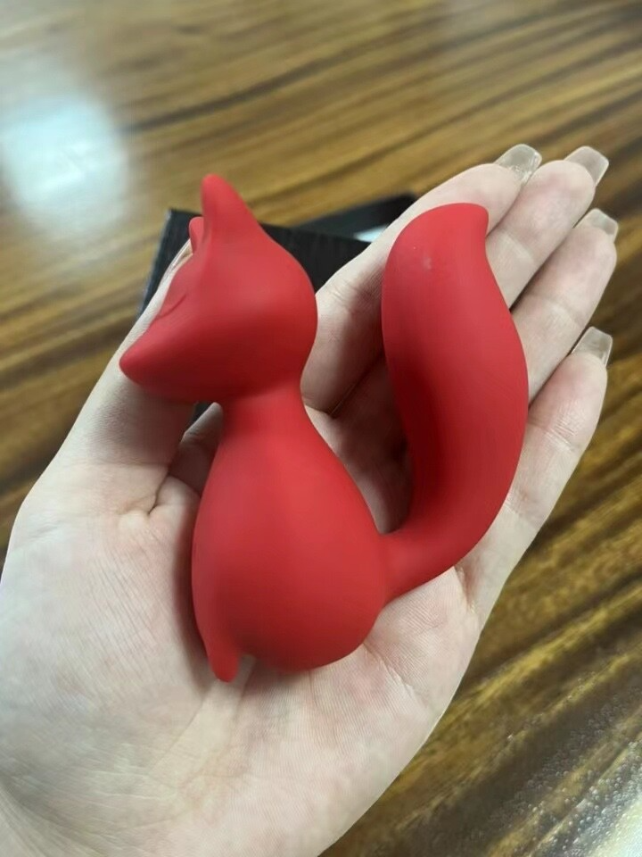 Red silicone object held in a hand on a wooden surface