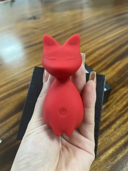 Red silicone product shaped like a cat held in a hand on a wooden surface
