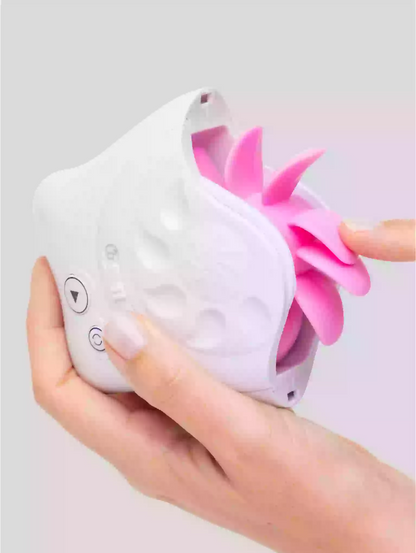 Hand holding a white device with a pink flower-like attachment on a light gray background