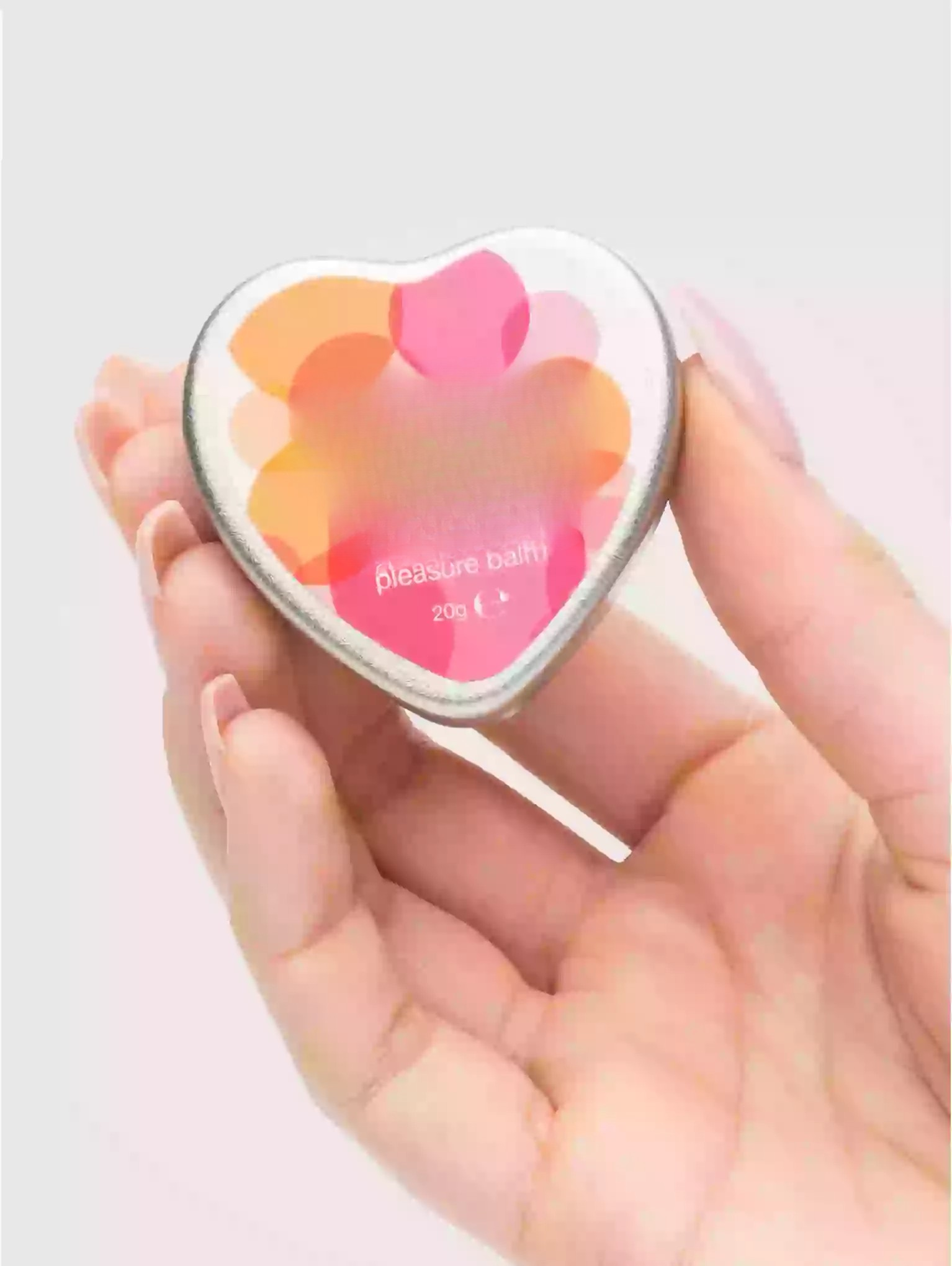 Heart-shaped compact mirror held in a hand with a light background
