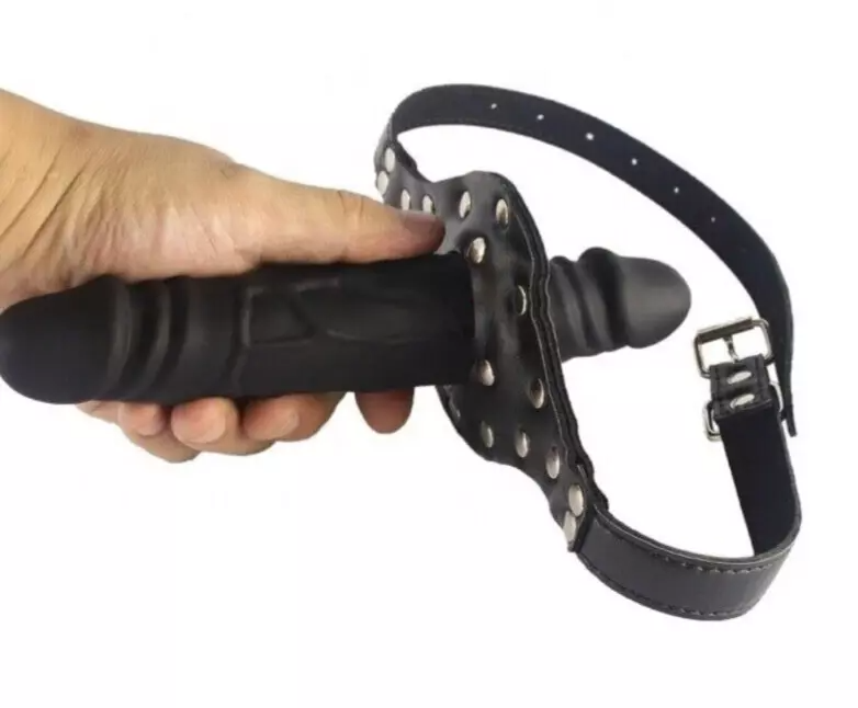 Hand holding a black leather dog muzzle with metal buckle on a white background