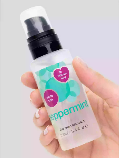 Hand holding a bottle of peppermint flavored lubricant with visible branding.