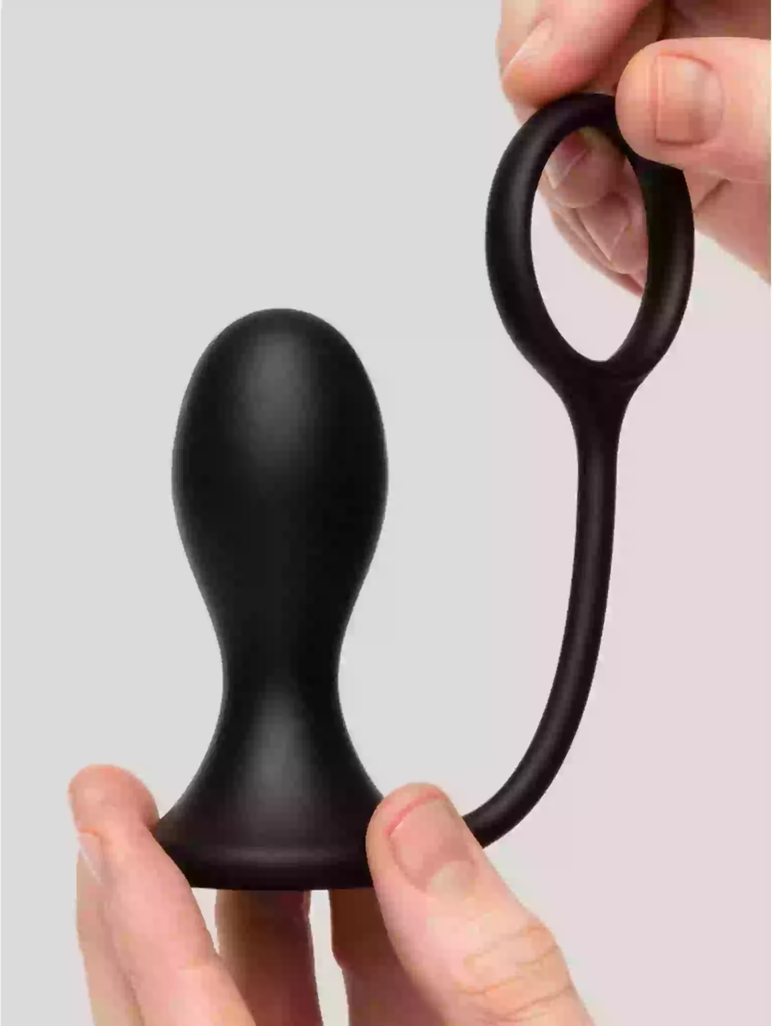 Black rubber toy held by a hand against a light gray background
