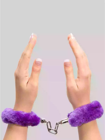 Purple fluffy handcuffs on a plain background