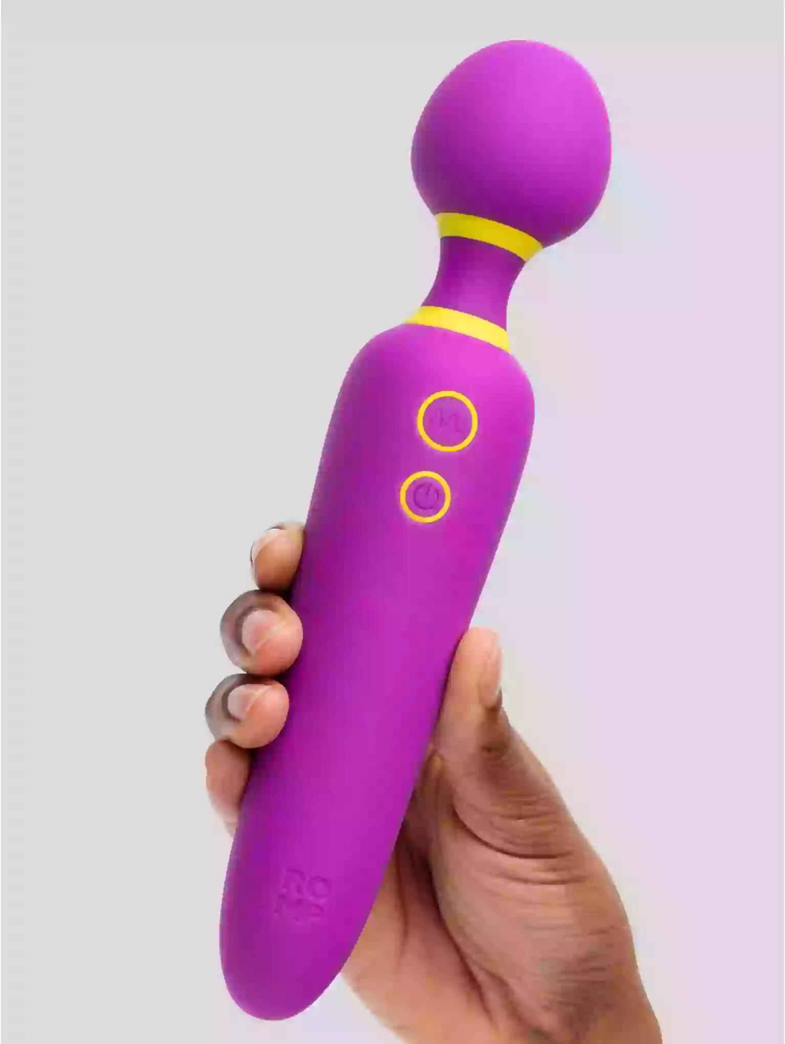 Purple and yellow toy held in a hand against a light gray background