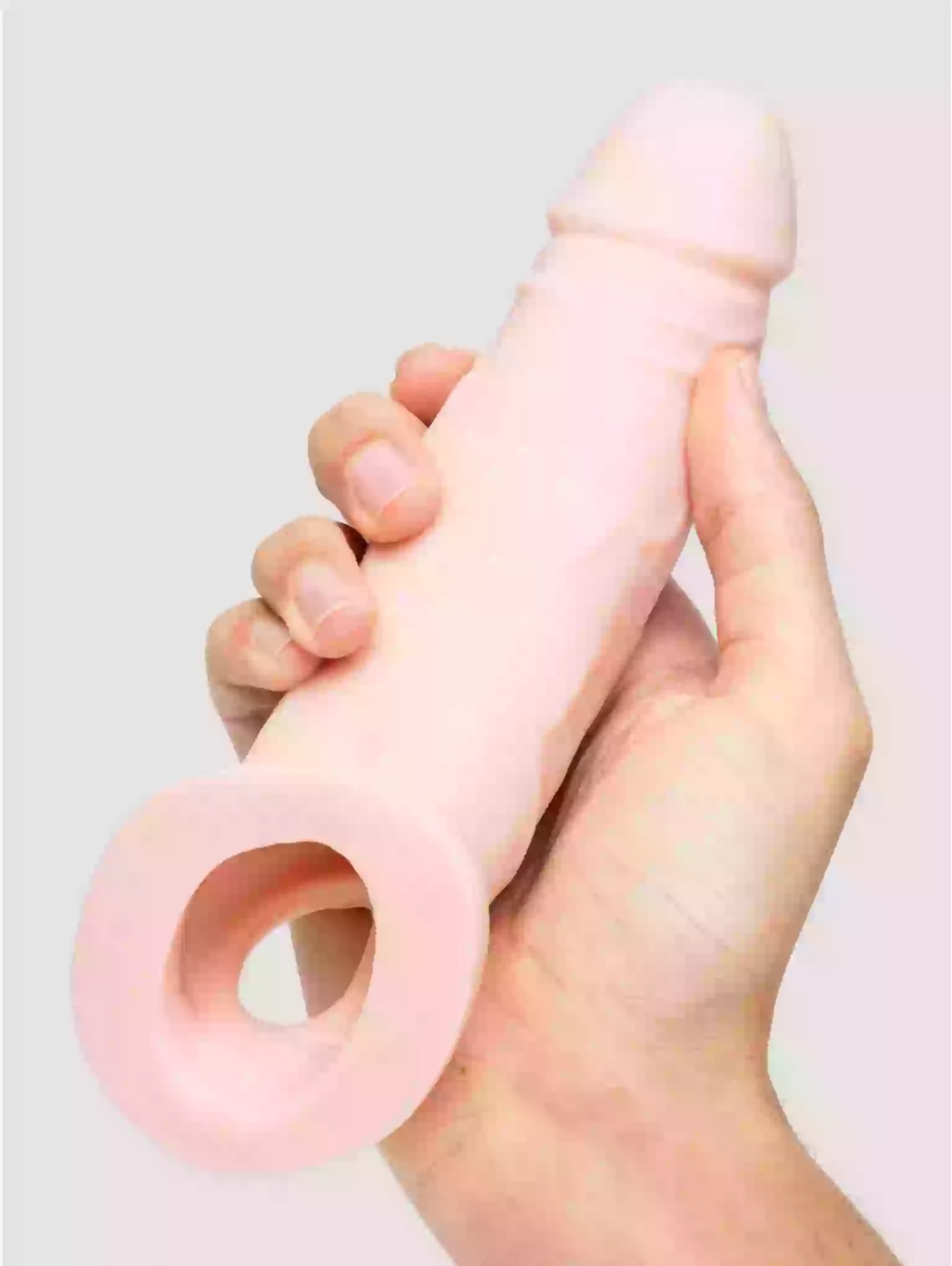 Hand holding a pink silicone ring against a light gray background