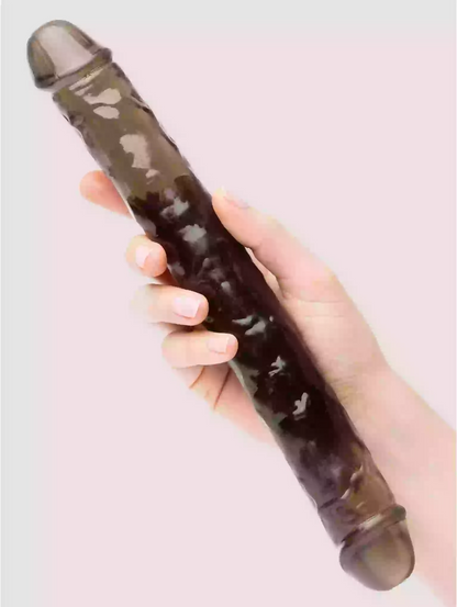 Hand holding a cylindrical object with a textured surface against a light pink background