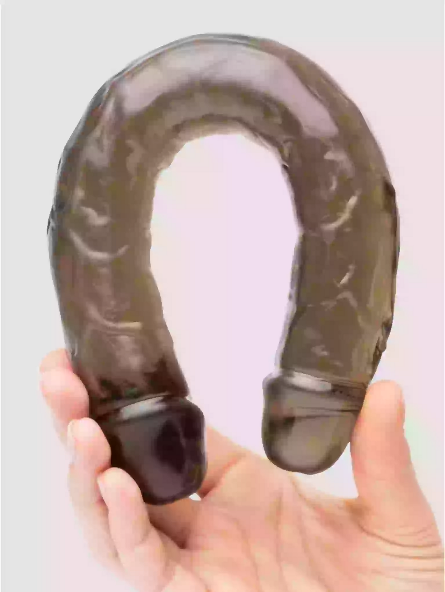 Hand holding a dark brown U-shaped object against a light background