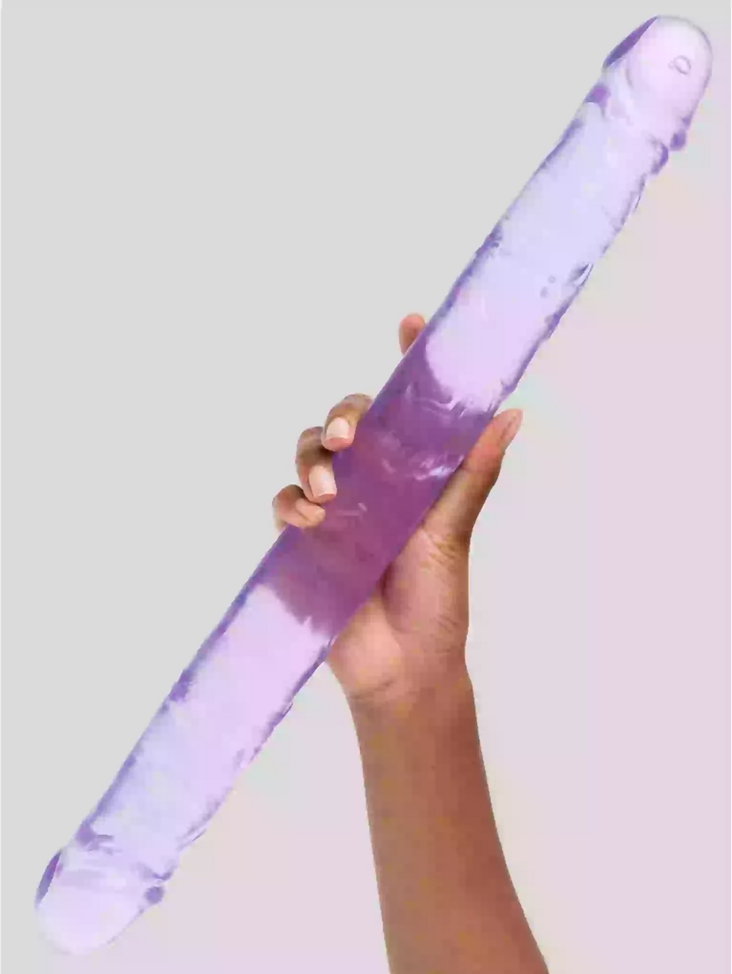 Hand holding a purple and clear cylindrical object against a light gray background