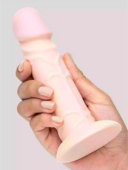 Hand holding a pink silicone product against a light gray background