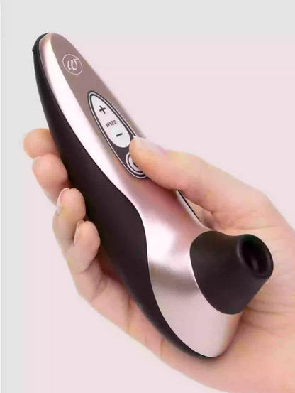 Hand holding a black and silver electronic device on a light gray background