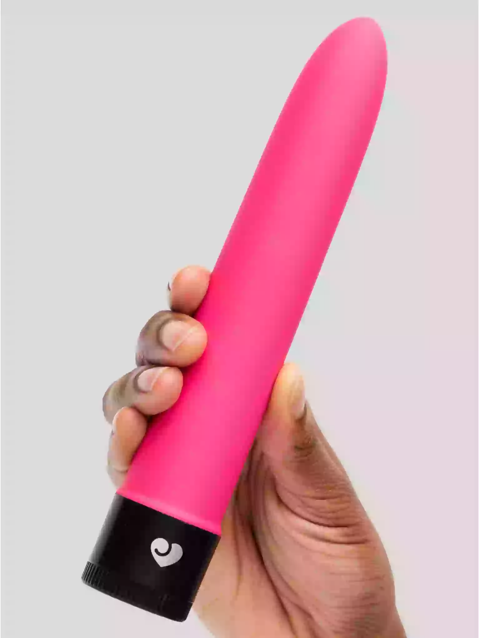Hand holding a pink and black object with a heart symbol on a light gray background
