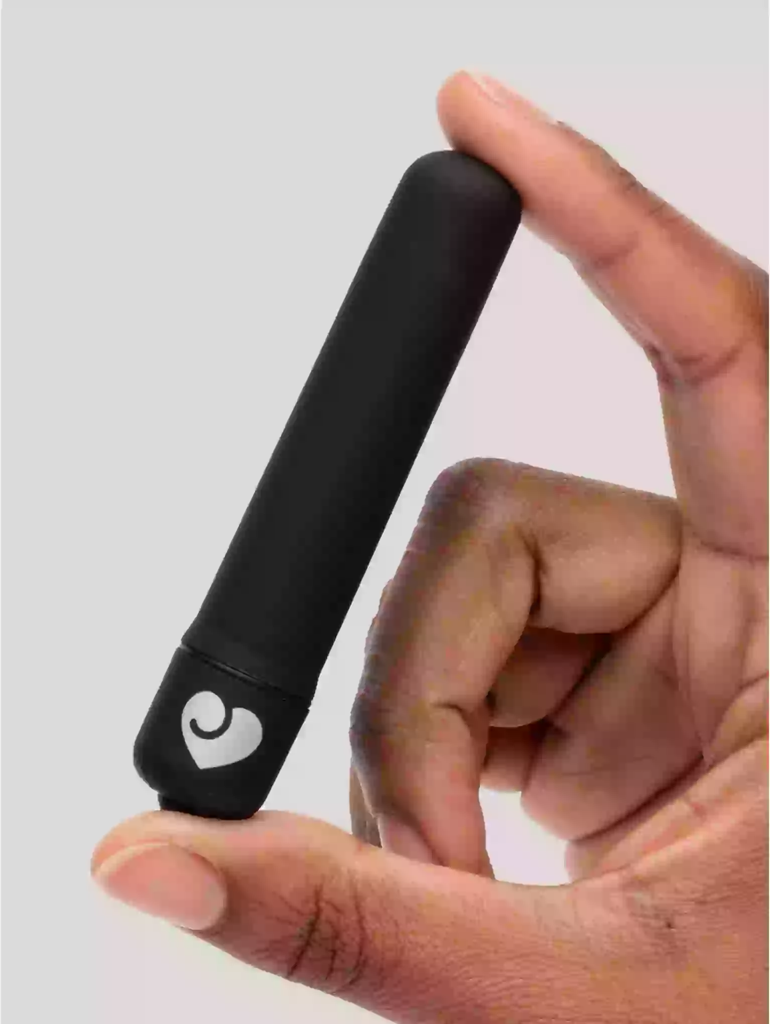 Hand holding a black cylindrical device with a heart symbol on a light gray background