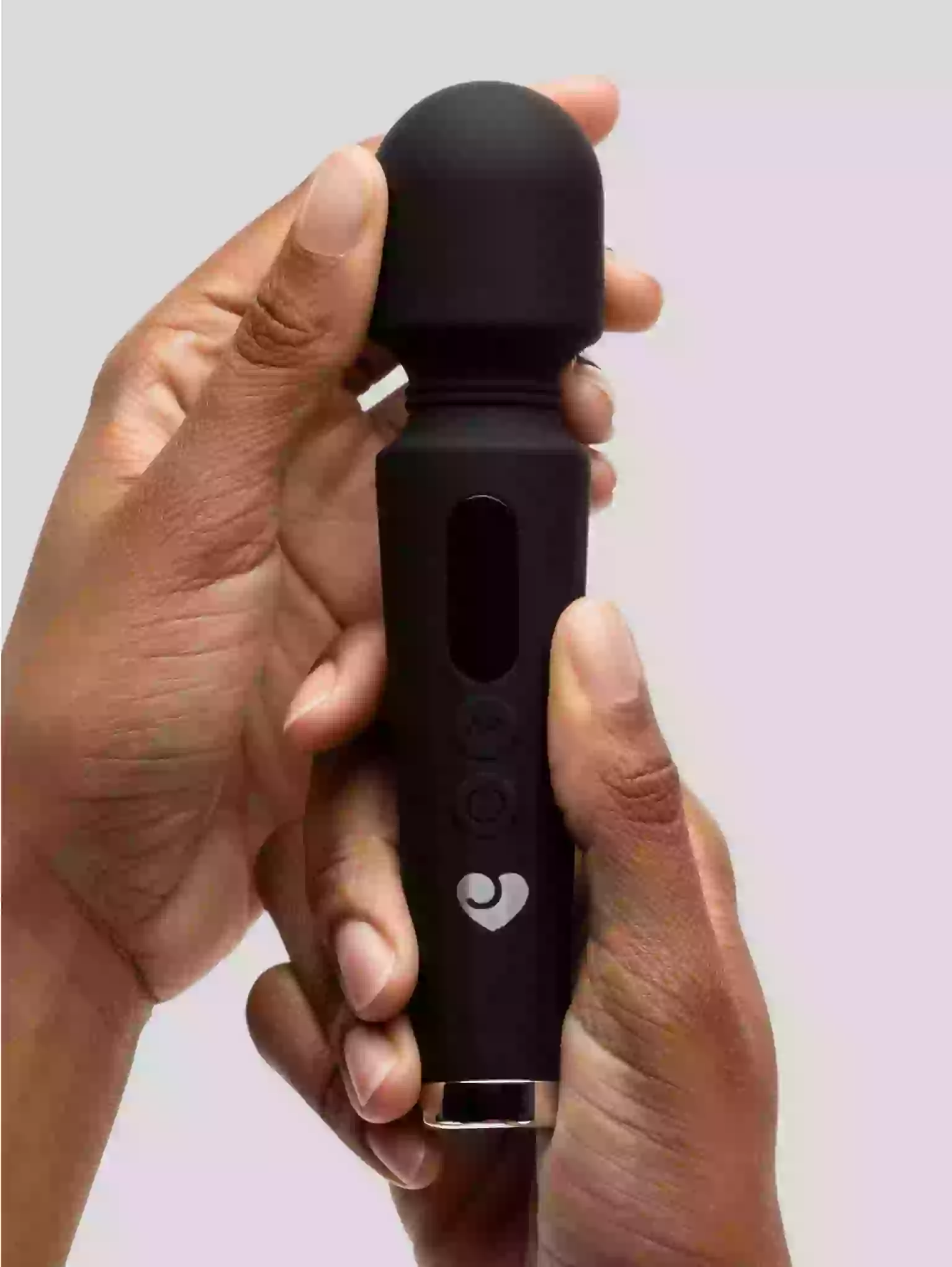 Black handheld electronic device held in a hand against a light background