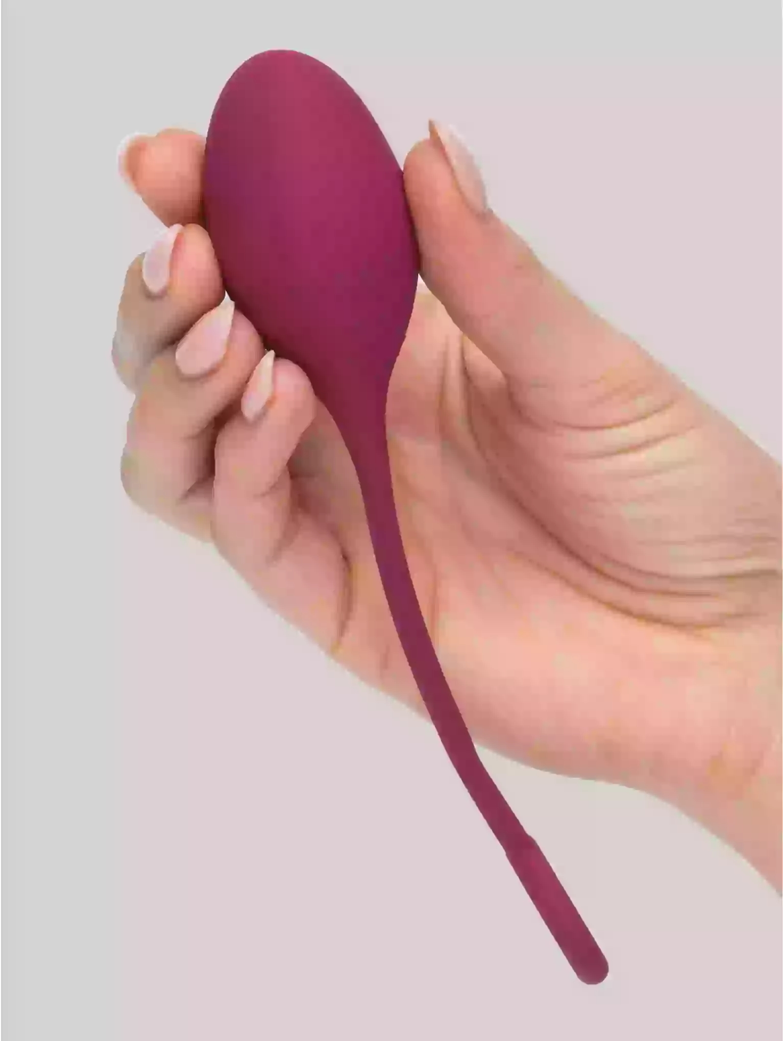 Hand holding a purple silicone tool against a light gray background