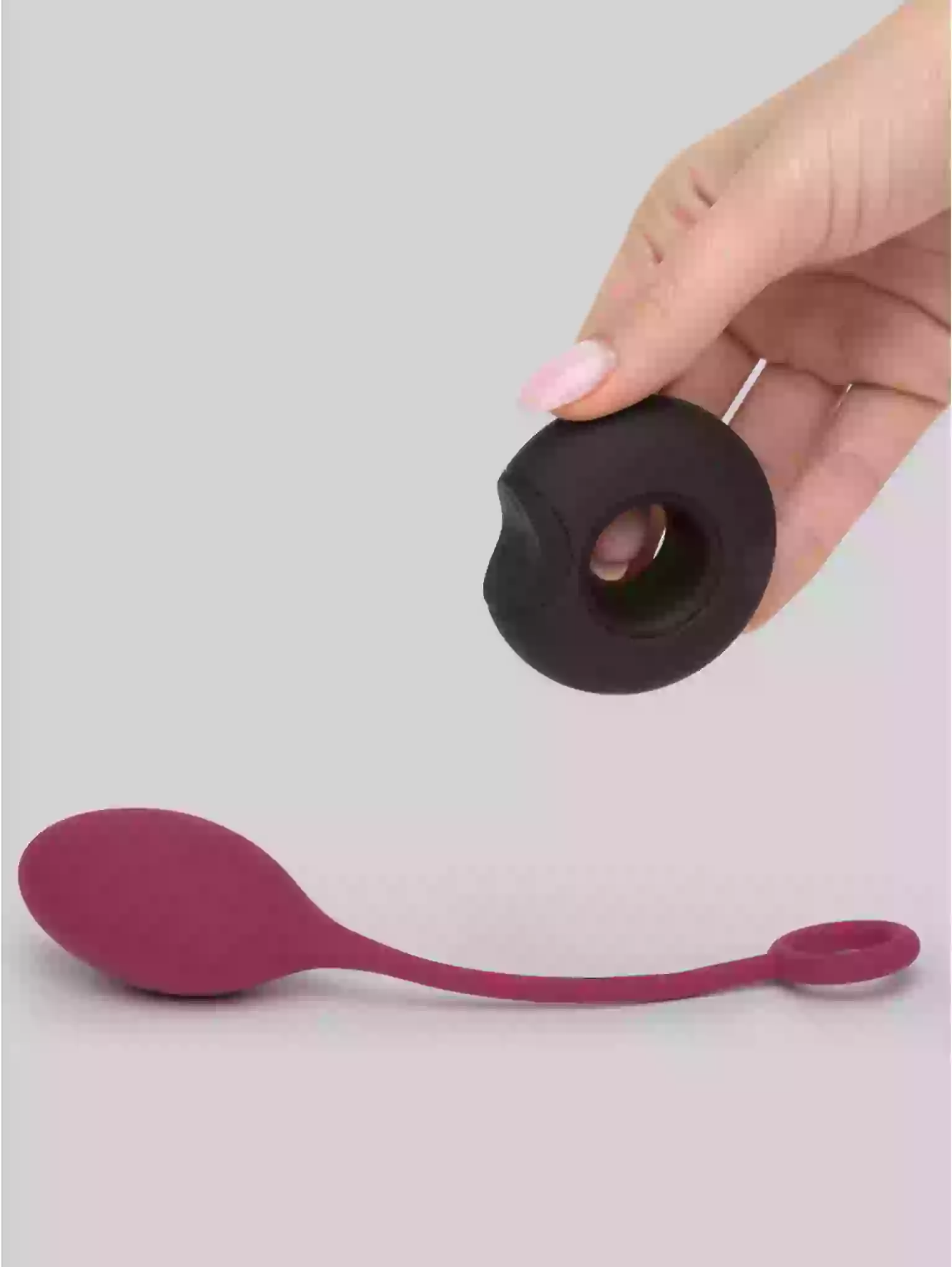 Hand holding a black and purple silicone tool against a gray background