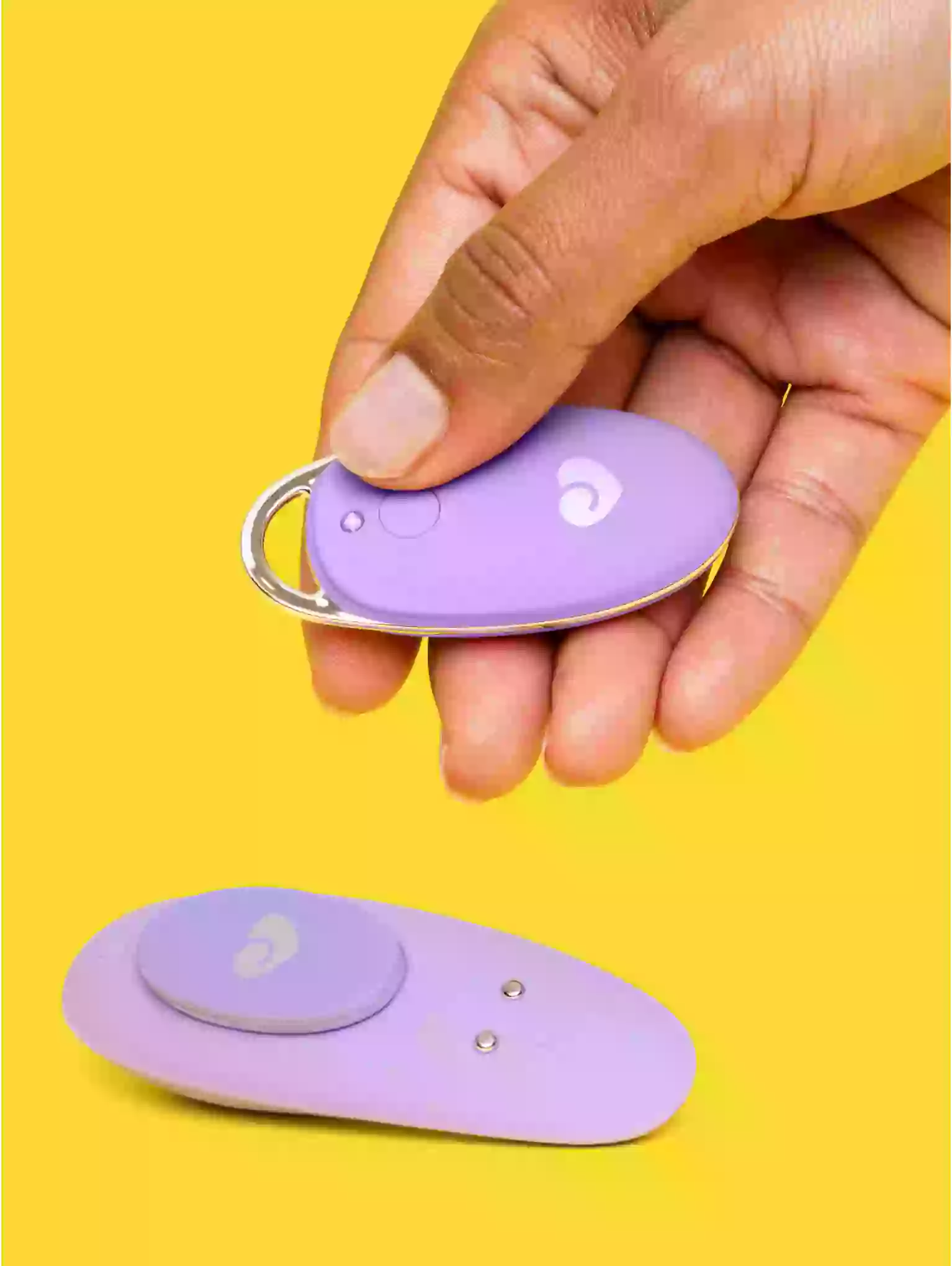Purple safety pendants held by a hand on a yellow background