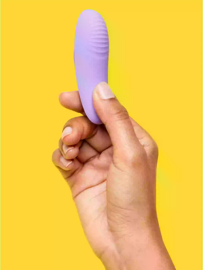 Hand holding a purple object against a yellow background