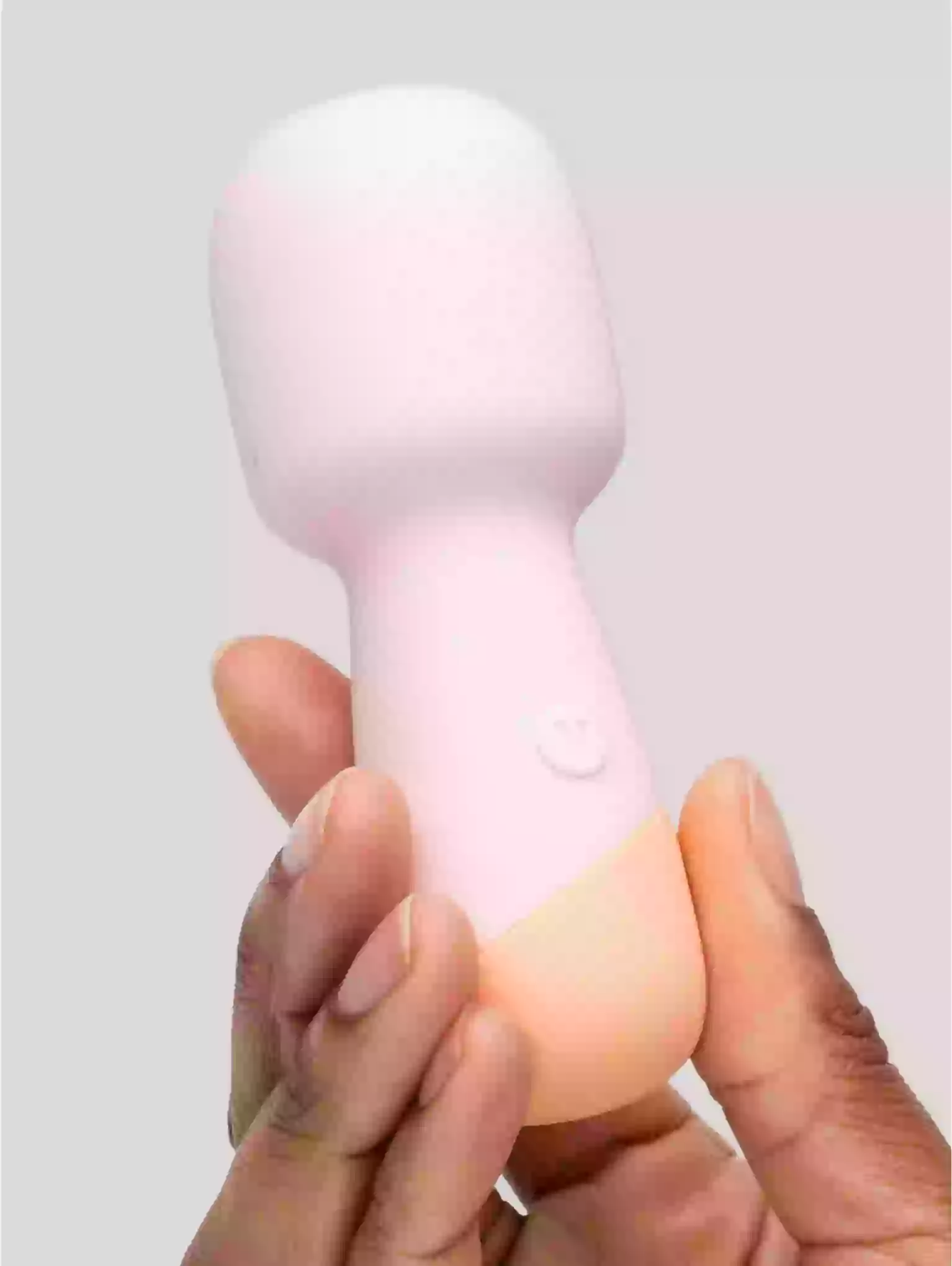 Pink and white handheld device held by a hand against a light gray background