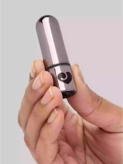 Hand holding a metallic cylindrical object with a heart design on a light gray background